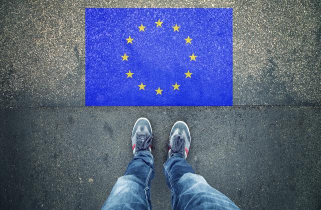 Feet standing of EU flag on pavement