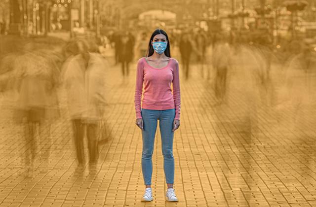 Woman in face mask alone in a crowded street