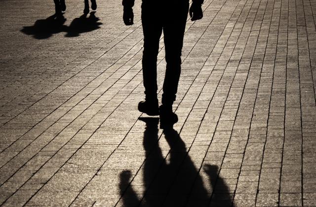 Shadow man walking towards a couple on a street