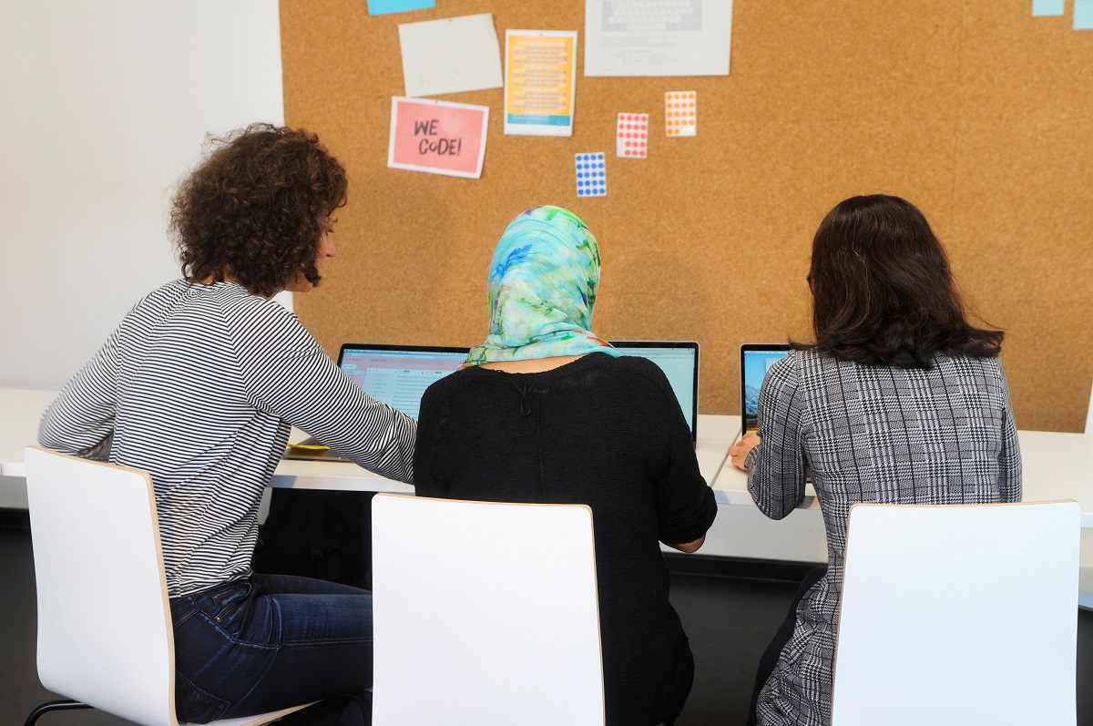 Three young women working together on laptops.