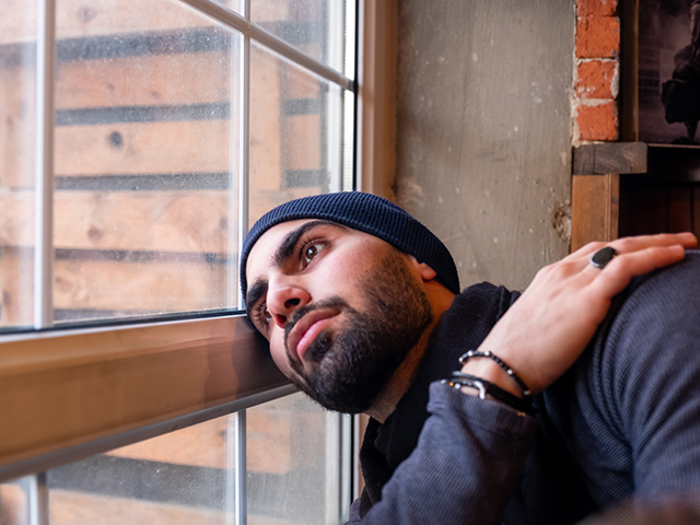 Sad muslim man looking out of a window