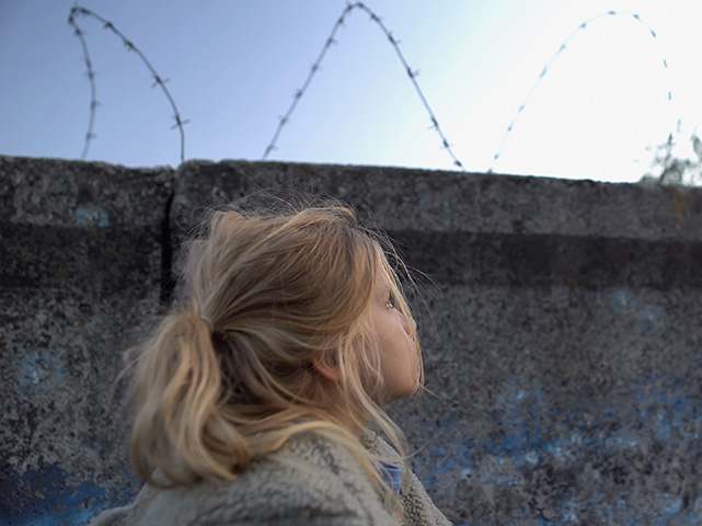 Girl at a migrant camp with wire
