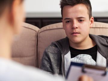 Young teenager boy at counseling - talking to the therapy professional, close up
