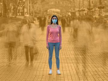 Woman in face mask alone in a crowded street