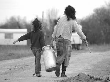 Two Traveller children carrying a container